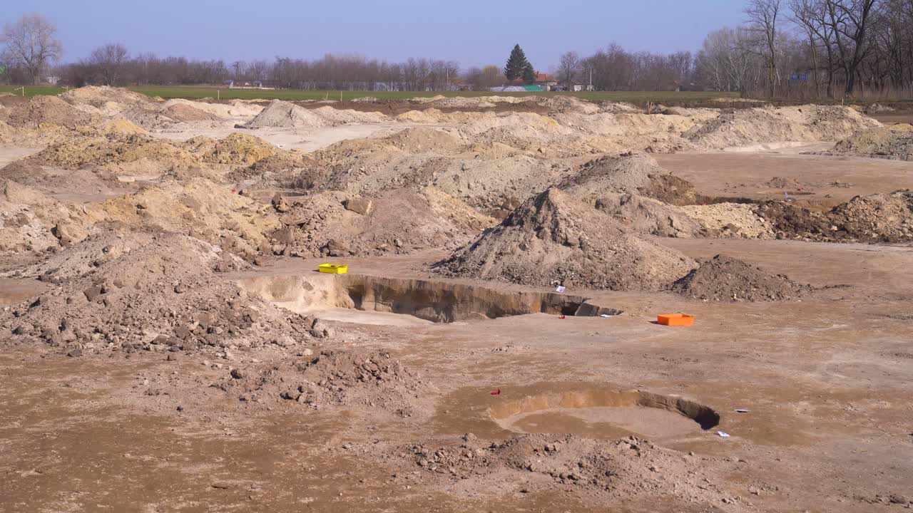 Establishing, static view of mounds of dirt, holes at archaeology site