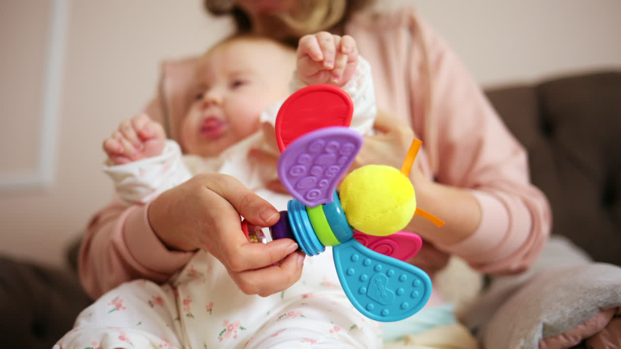 カラフルなおもちゃを使って自宅で赤ちゃんと遊んでいる笑顔の母親。
