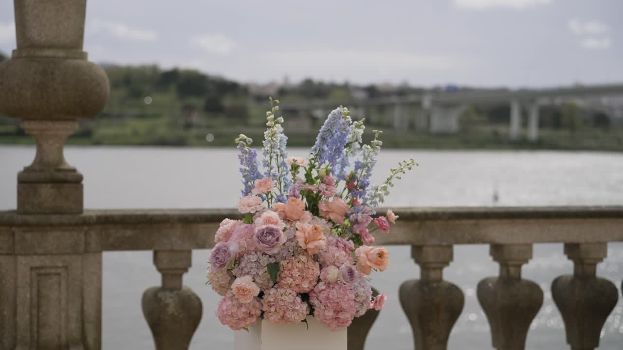 pastel flower bouquet stands on terrace with river in soft background