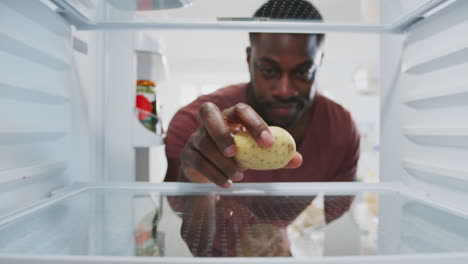 Un-Hombre-Decepcionado-Mirando-El-Interior-Del-Refrigerador-Vacío-Excepto-Por-Las-Patatas-En-El-Estante