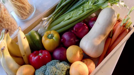 Crate-of-organic-vegetables-and-storage-jars-of-food-on-countertop-in-sunny-kitchen,-slow-motion