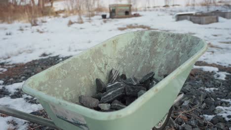 the man is loading rocks into the wheelbarrow for use in constructing a diy hot tub - timelapse