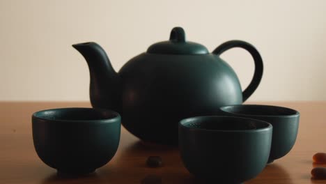 minimal background of a green japanese tea set with steam coming out of the cups, on a wooden table, with some stones around