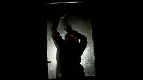 scary silhouette behind the door. woman behind the glass