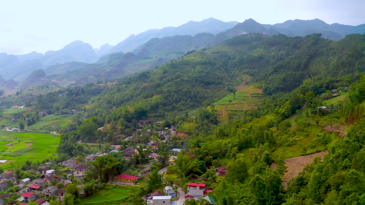 panorámica aérea a la derecha de una pequeña comunidad agrícola en las montañas brumosas del norte de vietnam.