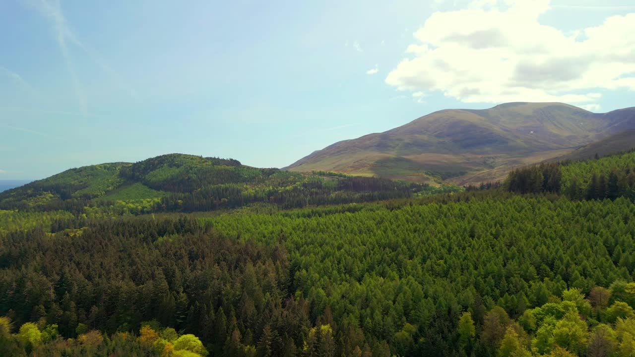 Forward travelling aerial video of the Mourne Mountains and Slieve Donard in Newcastle, County Down in Northern Ireland, UK on a bright and sunny day. Filmed in 4K, 60fps and with Rec709 Color.