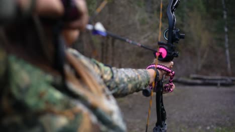 a girl holding a bow and arrow, pulling it back to firing position