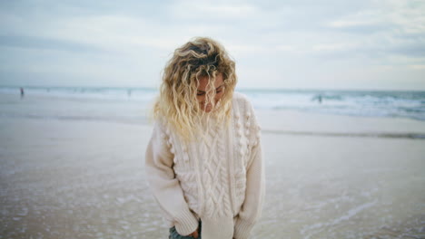 Happy-woman-enjoying-ocean-on-cold-autumn-weather.-Smiling-lady-walking-shore