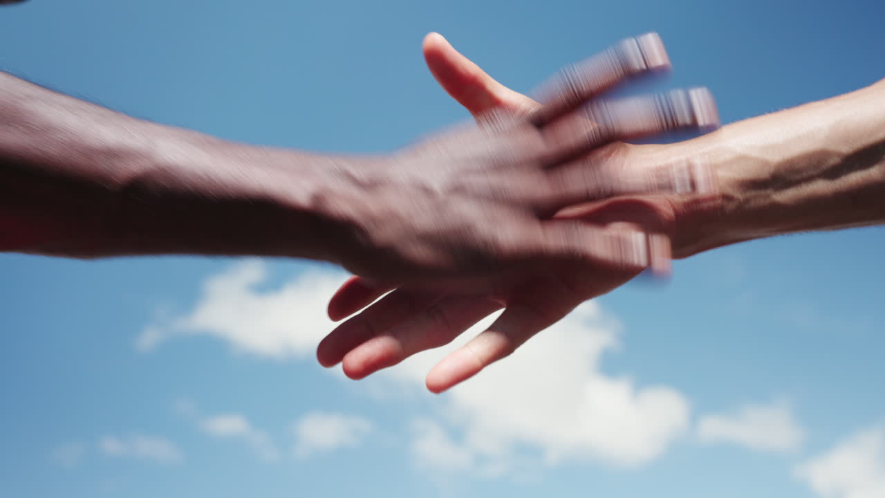 Diverse Hands Fist Bump and Shake in Unity Against Blue Sky