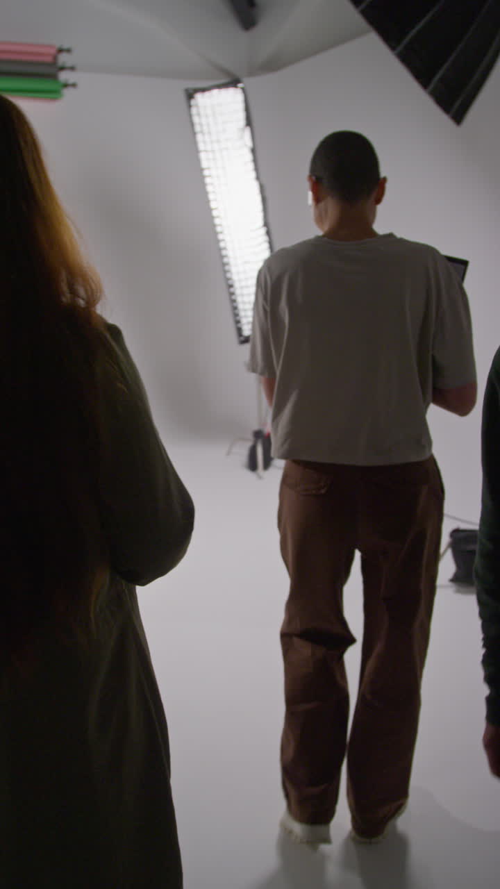 Vertical Video Of Film Director Talking With Male And Female Actors Holding Scripts Rehearsing For Shooting Movie Or Video In Studio 4