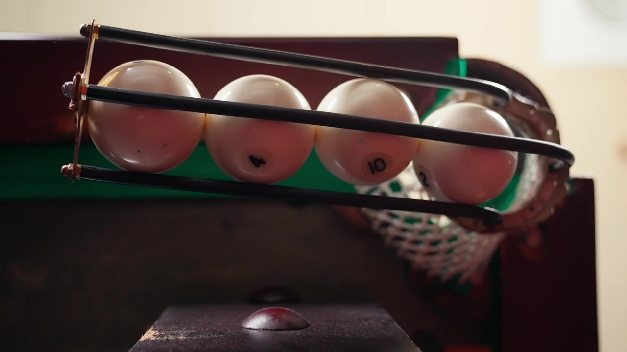 Nærbillede i slow motion af billardkugler der falder ned i et hul