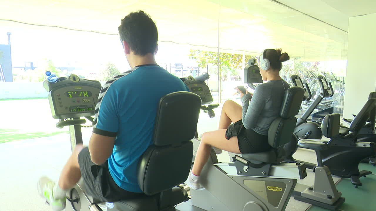 체육관 에서 운동 자전거 를 타고 운동 하는 사람 들