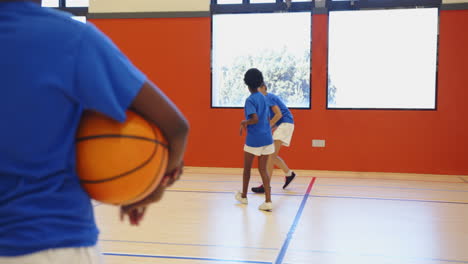 playing basketball in school gym, girls practicing dribbling and passing skills