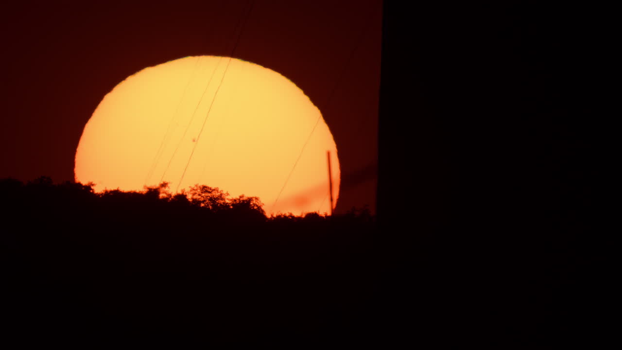 Stunning telephoto sunset view behind the trees and power lines in a cityscape setting