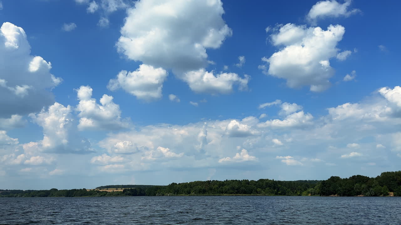 Beautiful blue summer sky with soft white clouds. Footage above the river surface on sunny day.