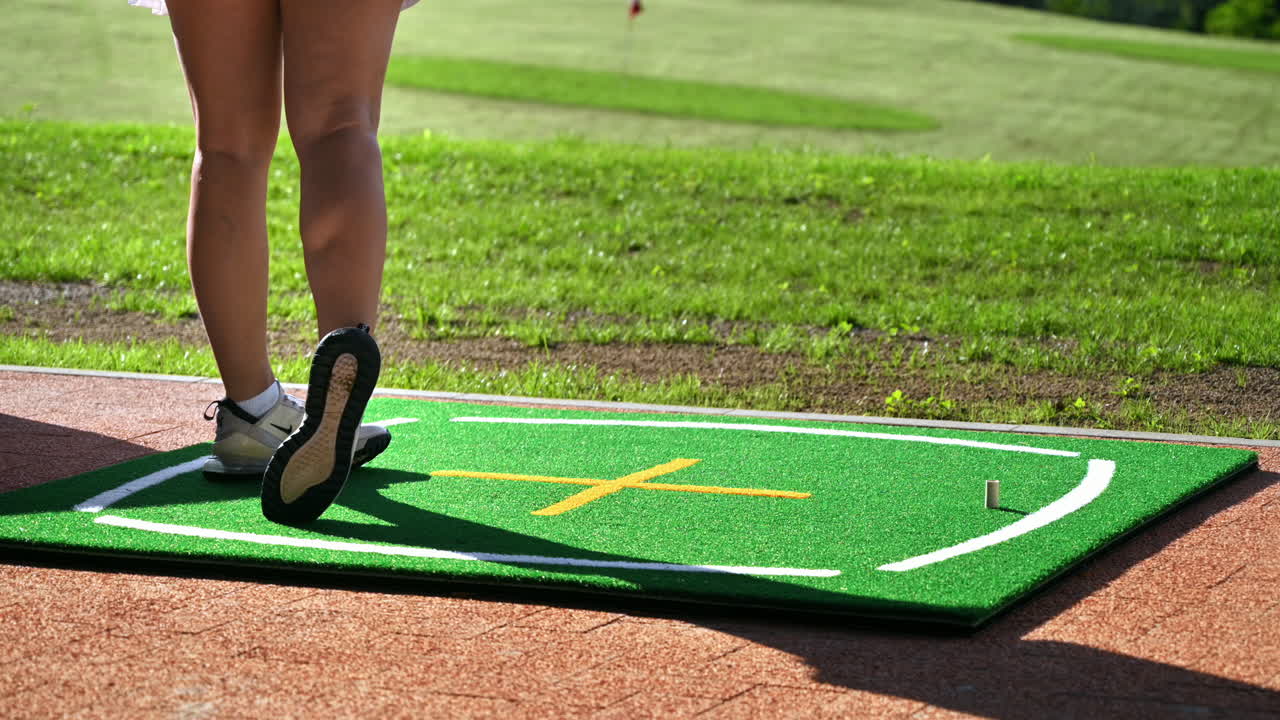 Donna in gonna bianca che gioca a golf su un campo in erba in una giornata di sole