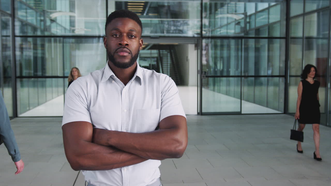Portrait Of Businessman Standing In Lobby Of Busy Modern Office
