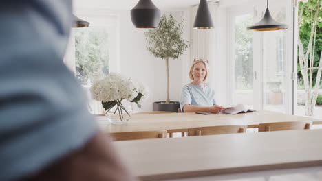 senior couple standing in kitchen and talking together as man chops carrots form meal