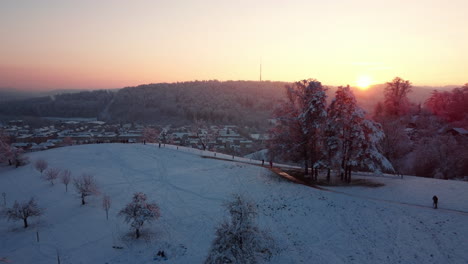 Vuelo-Sobre-Una-Romántica-Y-Cálida-Puesta-De-Sol-En-Un-Día-Nevado-De-Invierno-En-Winterthur,-Suiza