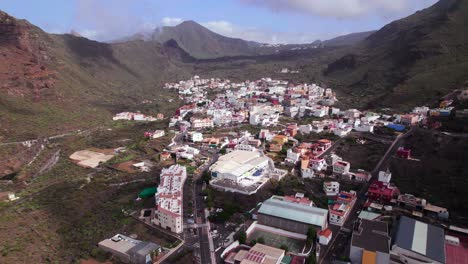 aerial tilt up reveal of a town in a green mountain landscape environment