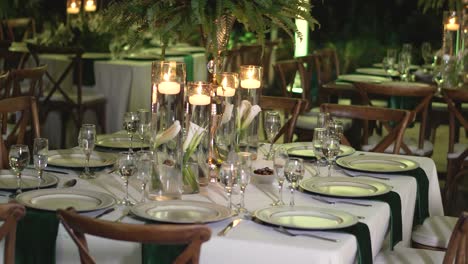 mesa decorada con piezas centrales de follaje natural, velas y artículos de vidrio para la recepción de bodas