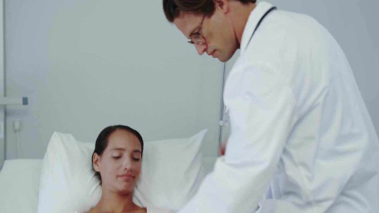 Vista frontal de médico caucasiano examinando paciente feminina na enfermaria do hospital 4K
