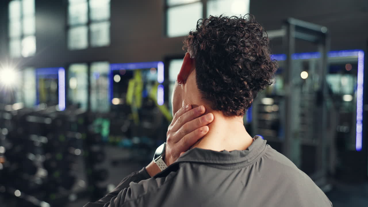 Man experiencing neck pain in the gym