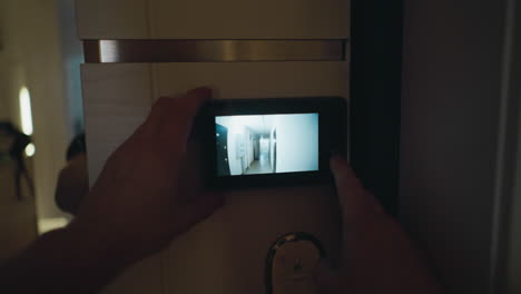 pov of a person using a digital peephole monitor to check the corridor outside their door for enhanced home security