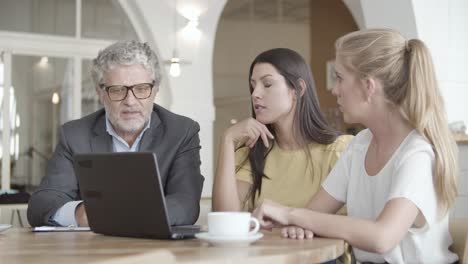 three professional partners sitting at table and discussing deal