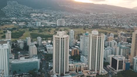 panning aerial drone slowly flying over a colorful honolulu skyline while sunset in oahu, hawaii with waikiki beach as a special point of interest.