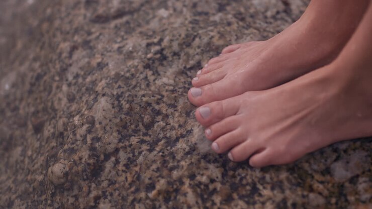 close up feet waves gently splashing barefoot woman standing on beach enjoying water touching toes refreshing ocean seaside vacation