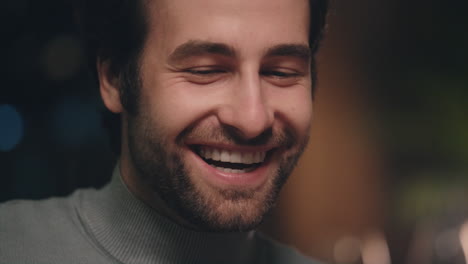 handsome man face smiling in soft light. positive guy enjoying conversation.