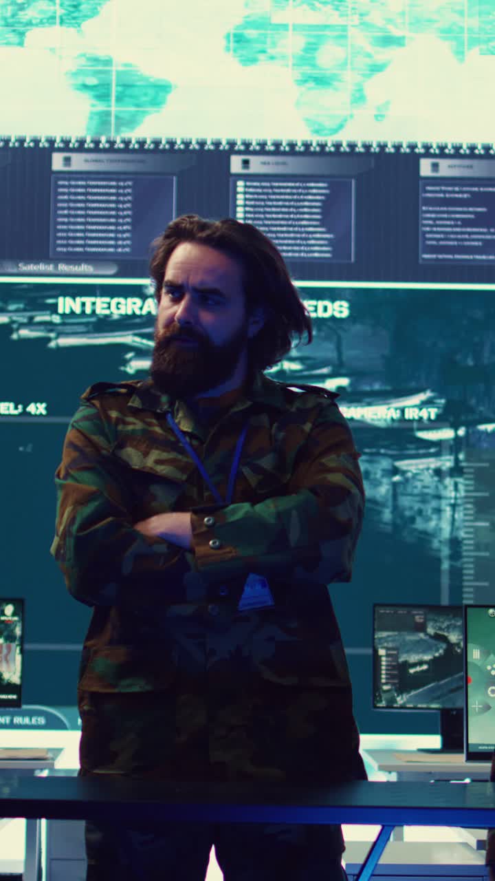 Bearded Man in Camouflage Jacket Standing in High-Tech Control Room
