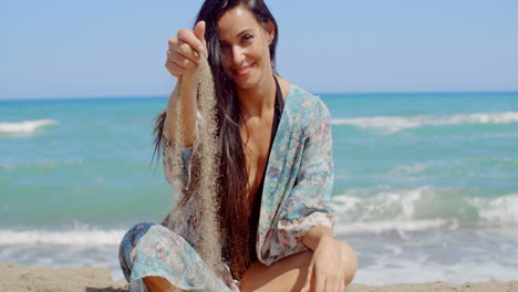 pretty lady sitting at the beach holding sand