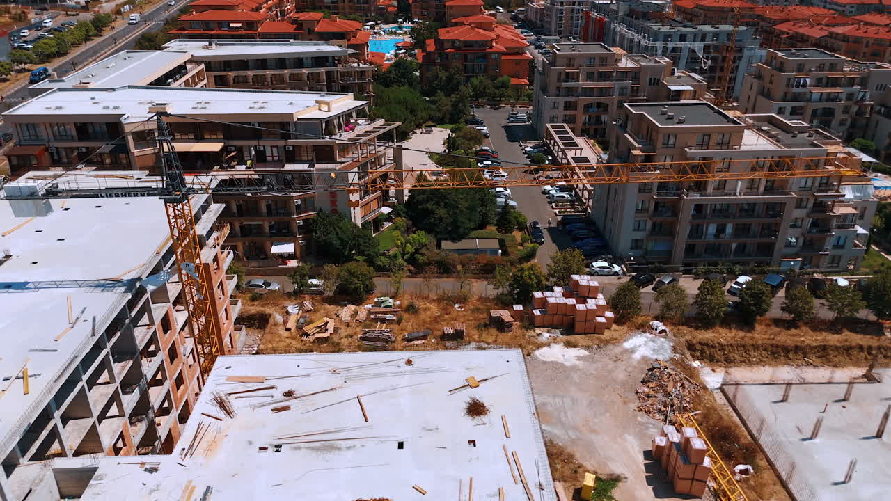 Construction progress near coastal area. New buildings are being developed in a bustling area, showcasing ongoing construction work under clear skies