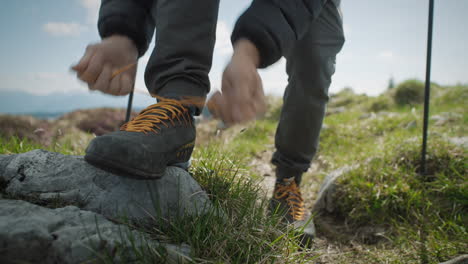 close up shot of hikers legs, walking towards the camera stopping putting his foot on the rock to tie his laces