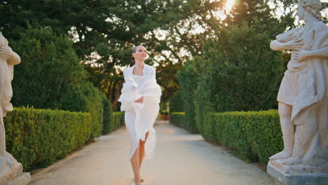 serene woman walking trail beautiful green garden with scarf swaying in wind.