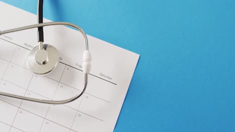 video of stethoscope on calendar, on blue background with copy space