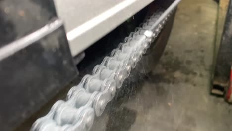 closeup of spraying motorbike chain with oil lubricant