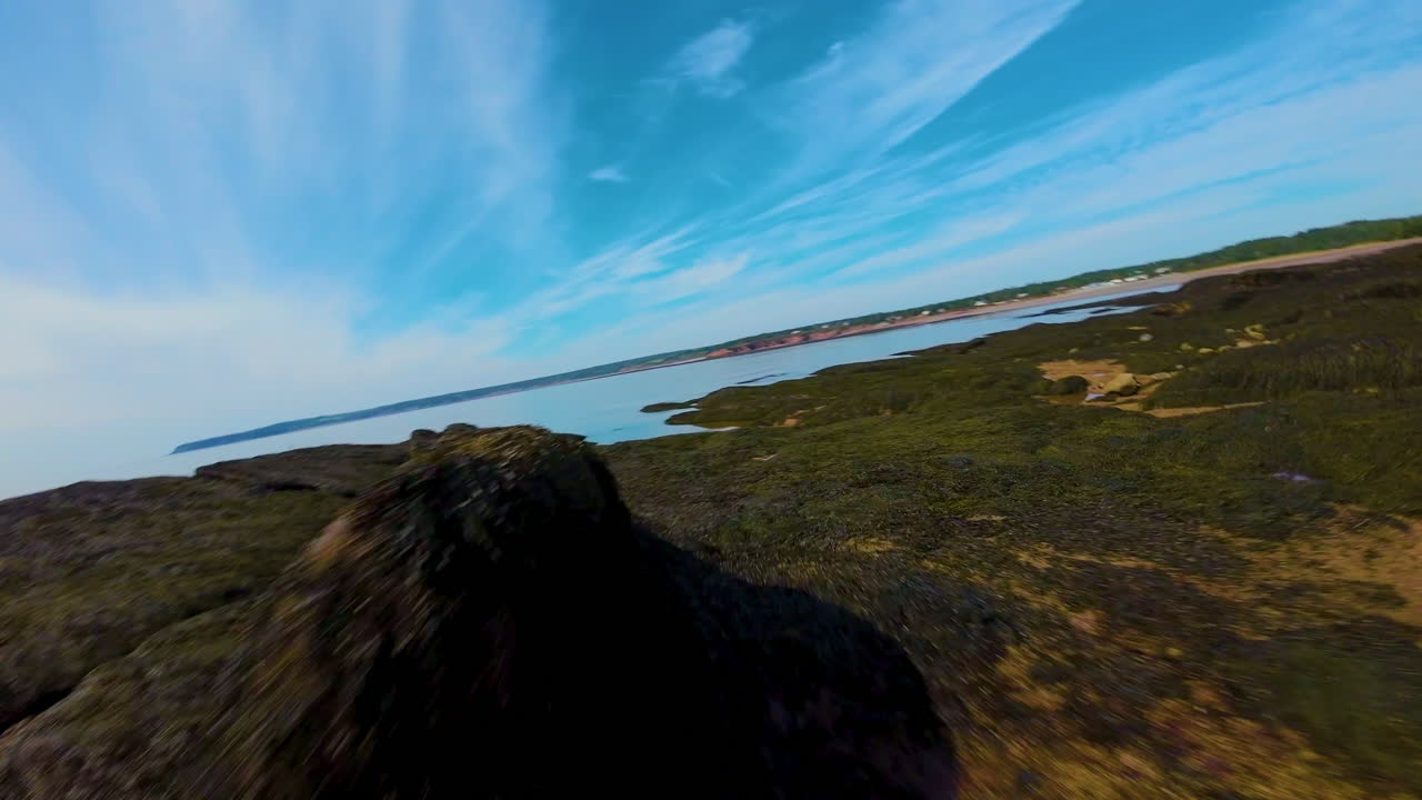 Beautiful aerial video sweeping across a coastal landscape of red rock cliffs on a bright clear day in Canada