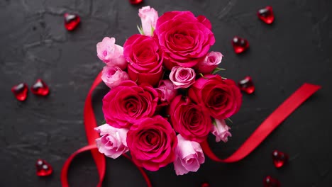 pink roses bouquet packed in red box and placed on black stone background