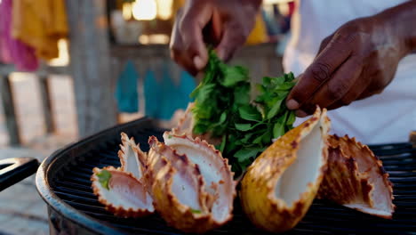 preparing grilled conch on a beach grill