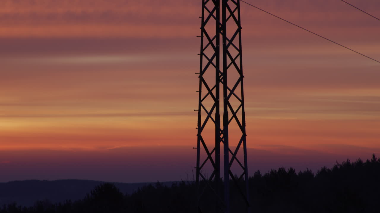 Medium shot of an electricity pylon at sunrise