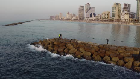 antena 4k - orbitando alrededor del hombre pescando en la playa de tel aviv - durante la puesta de sol