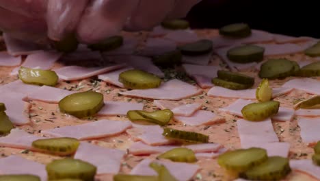 preparing a ham and pickle pizza