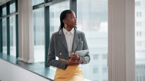 confident businesswoman with tablet looking out of window in modern office