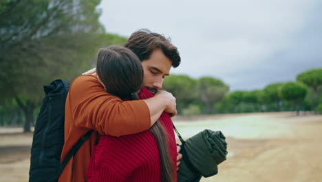 hikers hugging standing nature with backpacks close up. couple in love embracing