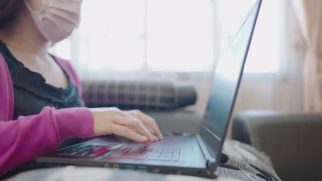 una mujer en primer plano sentada en un sofá escribiendo información en una computadora portátil para comprar en línea en casa