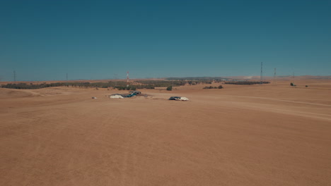 Tiendas-Beduinas-En-Un-área-árida-Y-Remota,-En-Un-Campo-De-Arena-Seco-Fuera-De-La-Red,-Cerca-De-Grandes-Líneas-Eléctricas-1