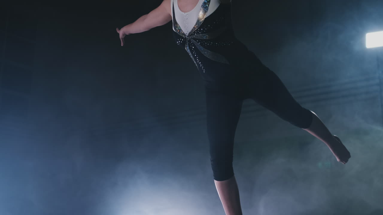In slow motion in the smoke, a girl athlete stands with her arms raised after performing exercises. Welcome gesture with your hands.